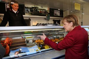 Angela Merkelová si kupuje rybu v obchode počas kampane v meste  Ribnitz-Damgarten pri Baltskom mori.