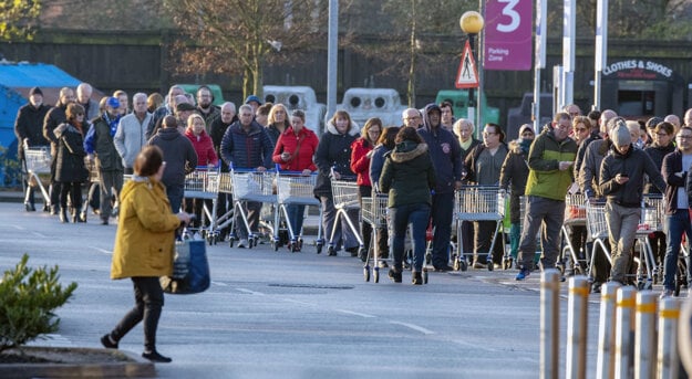 Zákazníci stoja v rade pred otvorením supermarketu v Liverpoole 20. marca 2020.