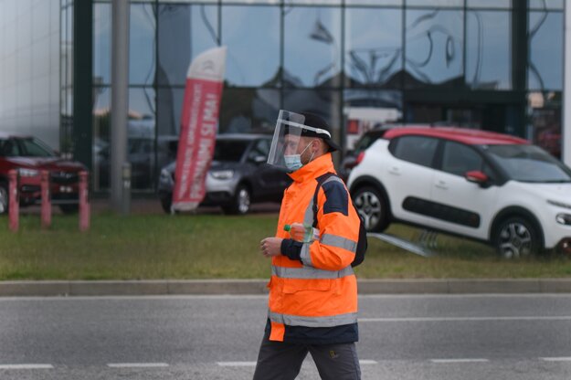Zamestnanec koncernu Groupe PSA s ochranným štítom prichádza do práce v Trnave.