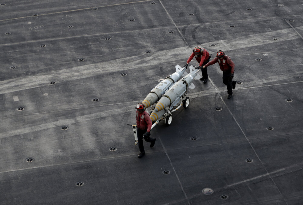 Palubný personál americkej lietadlovej lode USS Dwight D. Eisenhower tlačí vozík s bombami. FOTO - TASR/AP