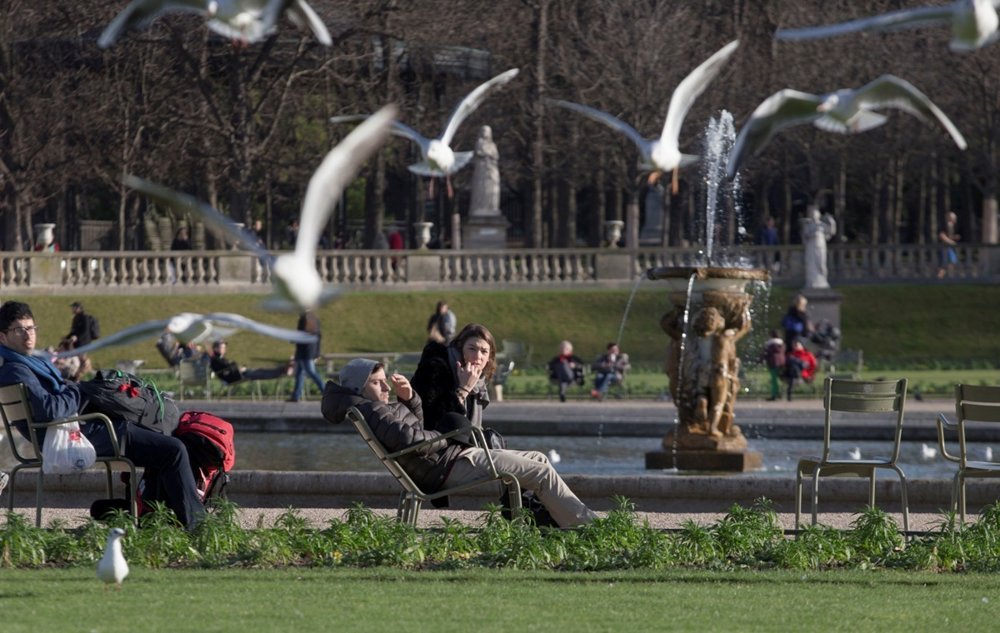 Ľudia relaxujú v príjemnom počasí v Luxemburských záhradách v Paríži.