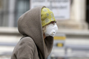 Žena s respirátorom na tvári kráča ulicou vo Viedni.