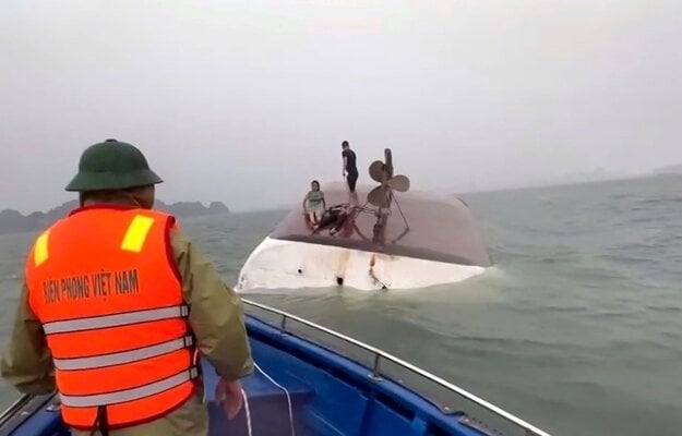 Snímka z videa poskytnutého QDND zobrazuje záchranu ľudí na prevrátenej turistickej lodi v zálive Ha Long. (zdroj: TASR/AP/QDND)