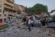 Ľudia odstraňujú trosky zrútenej budovy po zemetrasení v Sindirgi v severozápadnom Turecku.