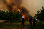  Ľudia bojujú s ohňom blížiacim sa k ich domom počas lesného požiaru v dedine Vounteni na predmestí mesta Patras