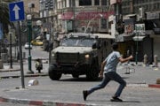 Palestínsky chlapec beží popred obrnené vozidlo izraelských síl na Západnom brehu Jordánu.