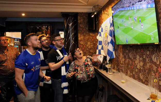 Futbaloví fanúšikovia Leicesteru City v jednom z miestnych barov sledujú priamy prenos zo stretnutia svojho tímu na pôde Manchesteru United.