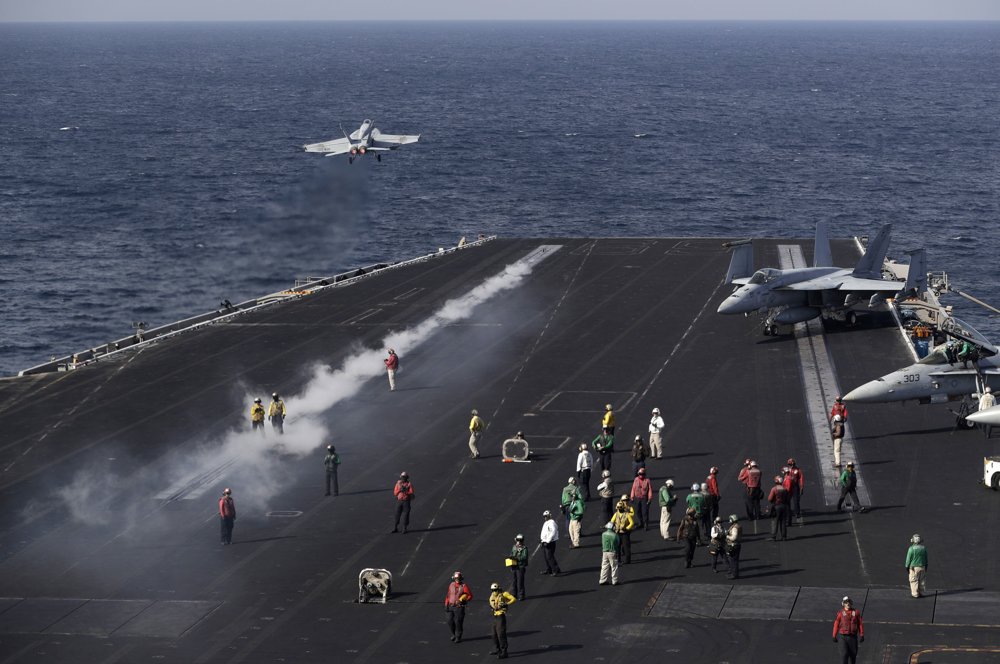 Palubný personál americkej lietadlovej lode USS Dwight D. Eisenhower sleduje štart stíhacieho lietadla amerického námorníctva F-18 Super Hornet. FOTO - TASR/AP