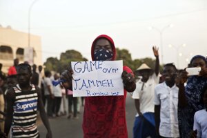 Muž v meste Serrekunda drží v rukách nápis "Je koniec, Jammeh." po tom, čo novozvolený prezident Gambie Adama Barrow zložil sľub.