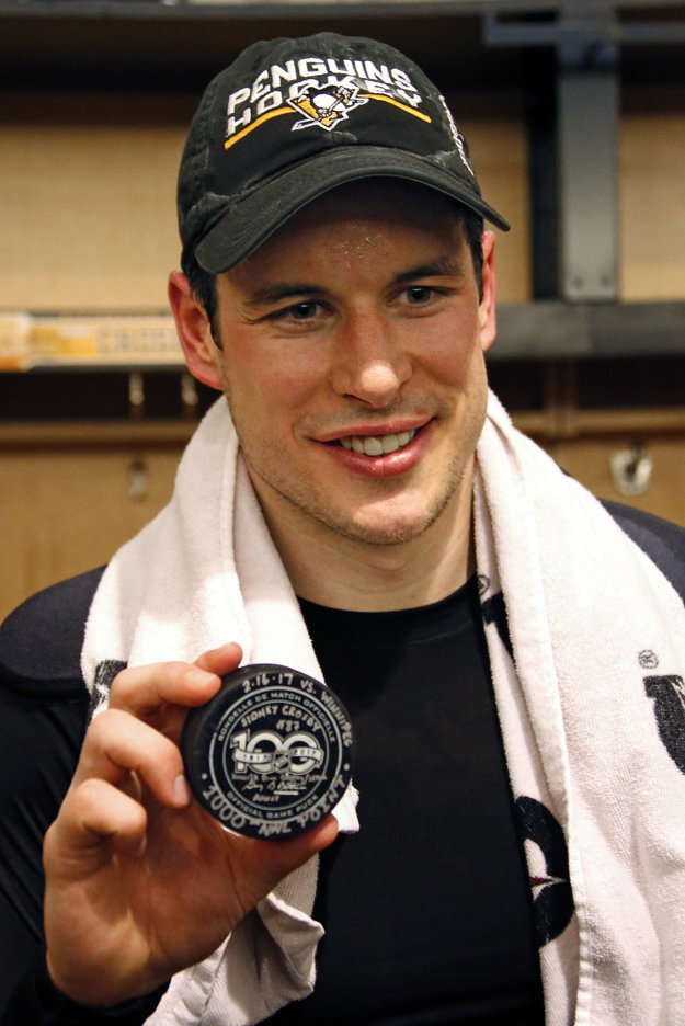 Kanadský hokejista a kapitán Pittsburghu Sidney Crosby pózuje s pukom po tom, čo pokoril hranicu 1000 bodov v kariére v zápase zámorskej hokejovej NHL Pittsburgh Penguins - Winnipeg Jets