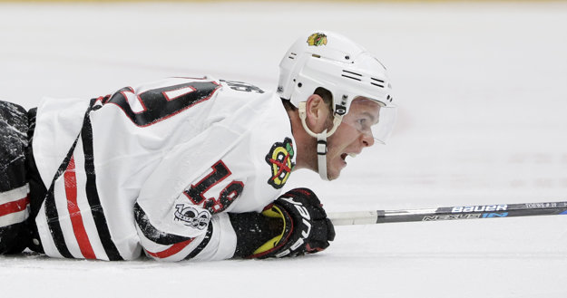 Kapitán Chicaga Jonathan Toews leží na ľade po jednom zo súbojov.