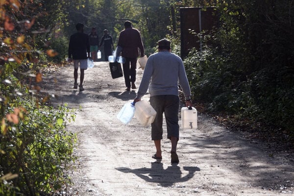 Migranti nesú prázdne kanistre na vodu pri utečeneckom tábore Vucjak 21. októbra 2019.