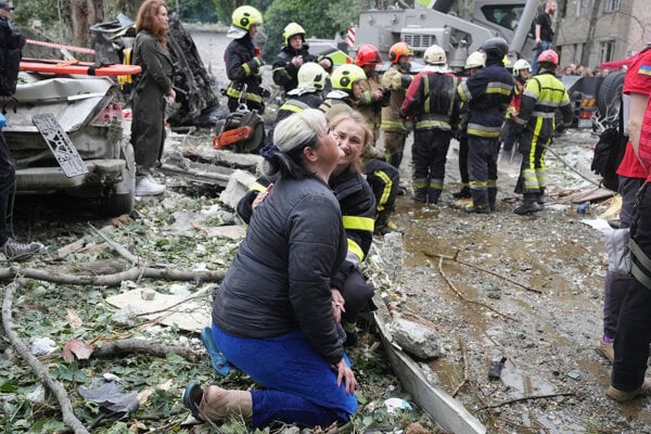 Záchranárka utešuje ženu, ktorá plače na mieste nočného ruského raketového útoku v Kyjeve.