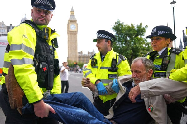 Policajt nesú muža počas protestu pre podporu propalestínskej skupiny v Londýne.