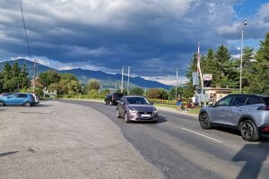 Po ceste v blízkosti športoviska prechádza auto za autom.