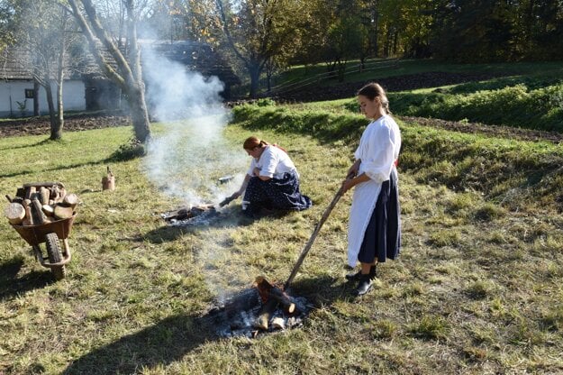 Women wearing folk costumes make campfire baked potatoes in Martin.