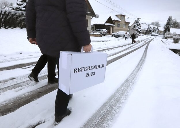 Members of a local referendum commission carry a ballot box in the village of Bacúrov, central Slovakia, on January 21, 2023.