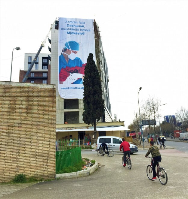 Street scene in Tirana. The billboard says: “Give your heart to love, and for your lungs trust Medicine.” 