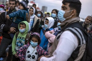 Refugees and migrants waiting for a bus at the port of Piraeus near Athens on May 4, 2020. 