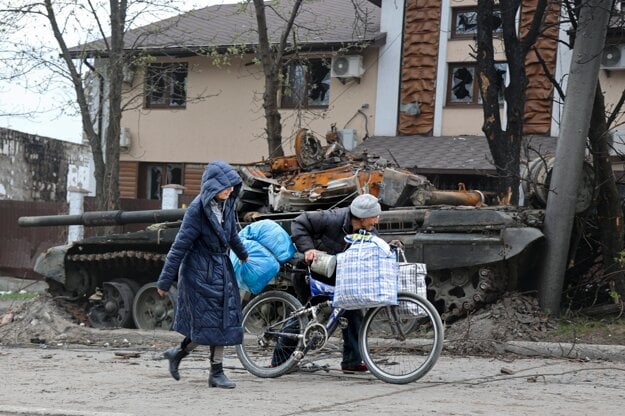 Local civilians walk past a tank destroyed during heavy fighting in an area controlled by Russian-backed separatist forces in Mariupol, Ukraine, on April 19, 2022.