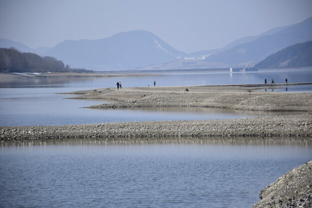 The Liptovská Mara dam has attracted hundreds of people these days. The water level is lowered due to the expected melting of snow in the mountains. People can thus walk on the remains of a former road connecting flooded villages.