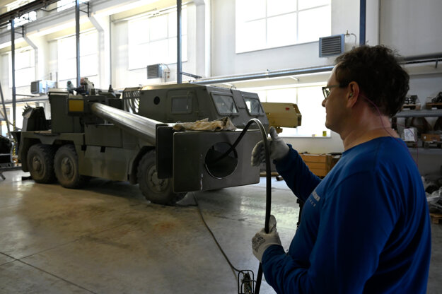 A worker cleans the gun barrel of an armoured vehicle.