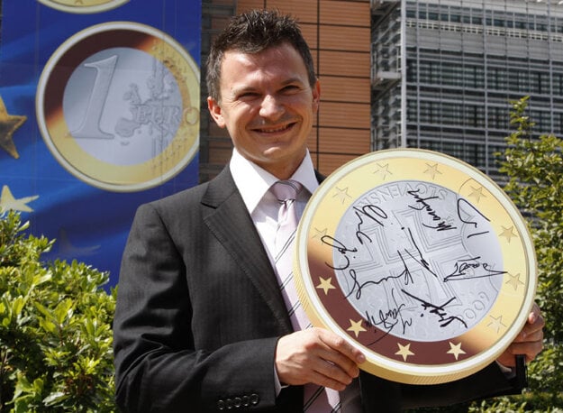 Ján Počiatek as finance minister in 2008, posing with a mock-up of a Slovak euro coin in Brussels after the final crown–euro conversion rate was confirmed.