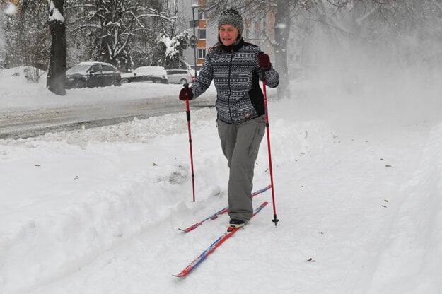 A woman is cross-country skiing on a sidewalk during a snowfall in Prešov on February 11, 2021. 