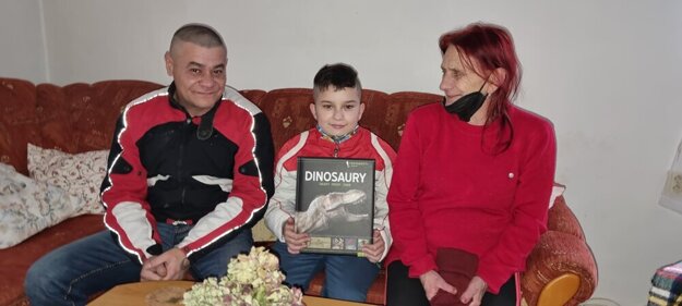 Radko je usilovný žiak, najradšej číta encyklopédie o dinosauroch. Po pravej strane jeho babka.